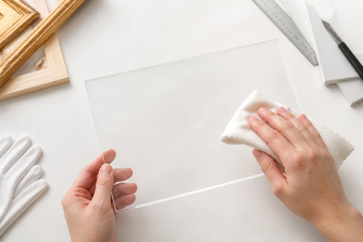 Plaque de plexiglas transparent manipulée avec un chiffon microfibre en atelier