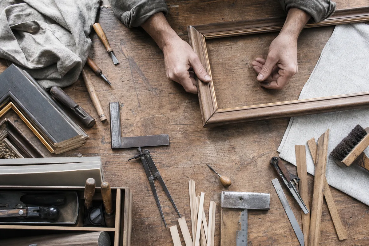 Artisan encadreur ajustant une baguette sur un établi encombré d&rsquo;outils